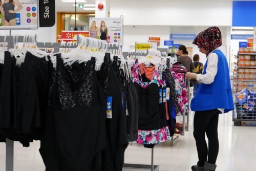 Un empleado revisa la etiqueta de precio en la ropa que se exhibe a la venta en una tienda Walmart
